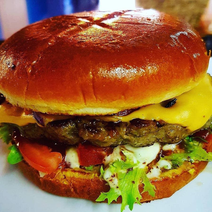 Close-up of a cheeseburger in a glazed brioche bun with lettuce and tomato