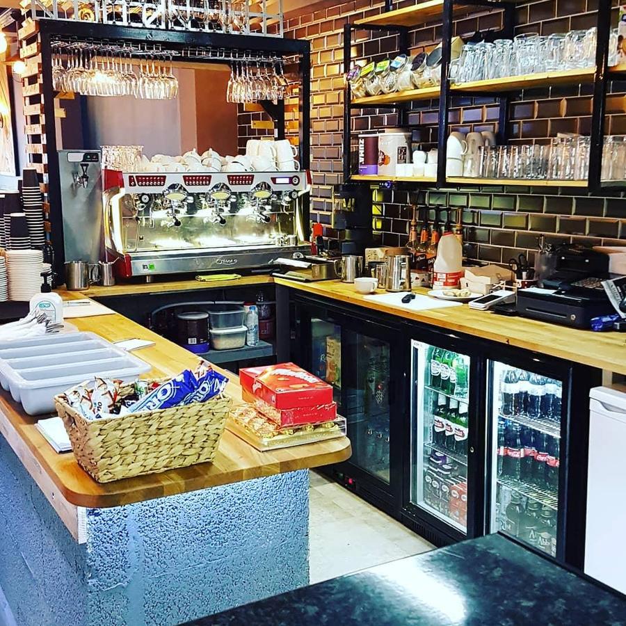 Behind the counter at On A Plate: espresso machine, hanging glassware, metro-tiled wall and oak worktops
